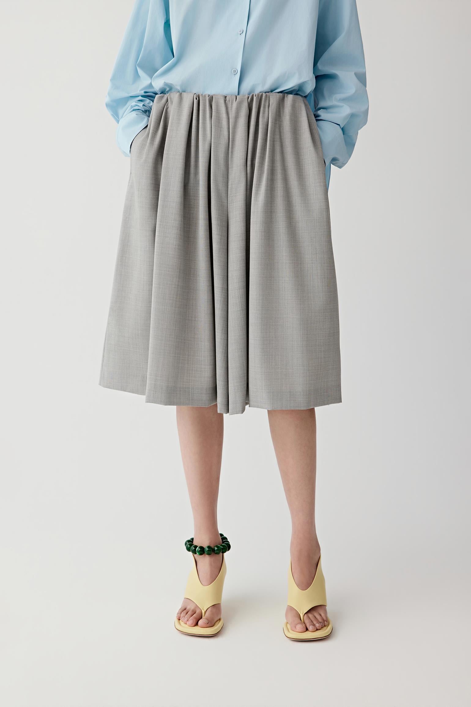 Woman wearing a light blue shirt and gray short on a white background