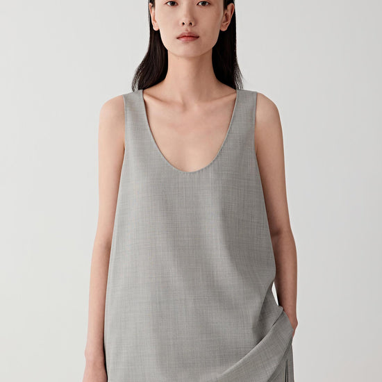 Video showing the model turning slightly while wearing the sleeveless wool top, revealing the fluid drape of the lightweight fabric and the soft movement of the pleated skirt.