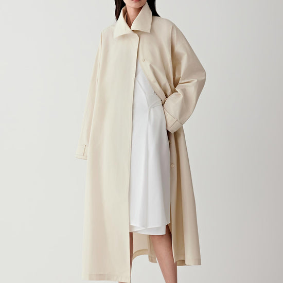 Woman wearing a beige trench coat on a white background