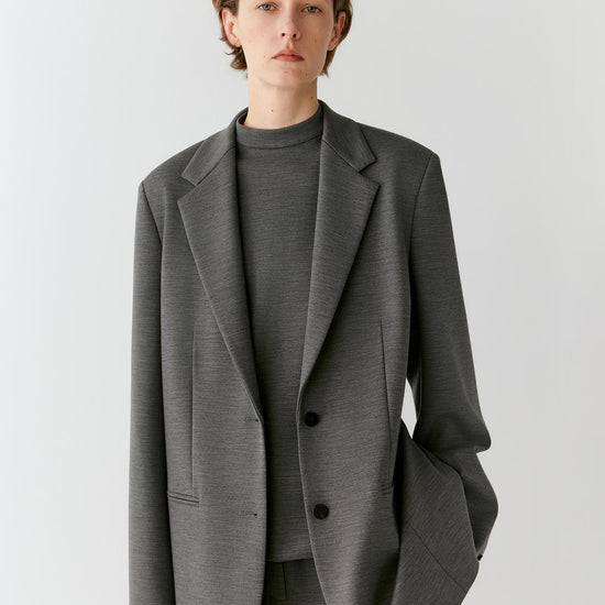 Video of a woman wearing a dark grey melange wool blazer, showing the relaxed silhouette and movement of the Ponte di Roma jersey as she moves.