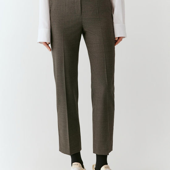 Video of a woman wearing grey melange wool suiting trousers, showing the movement of the bootcut silhouette and structured fabric as she moves.