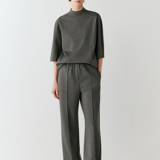 Video of a woman wearing a dark grey melange wool T-shirt, showing the elongated relaxed silhouette and movement of the Ponte di Roma jersey as she moves.