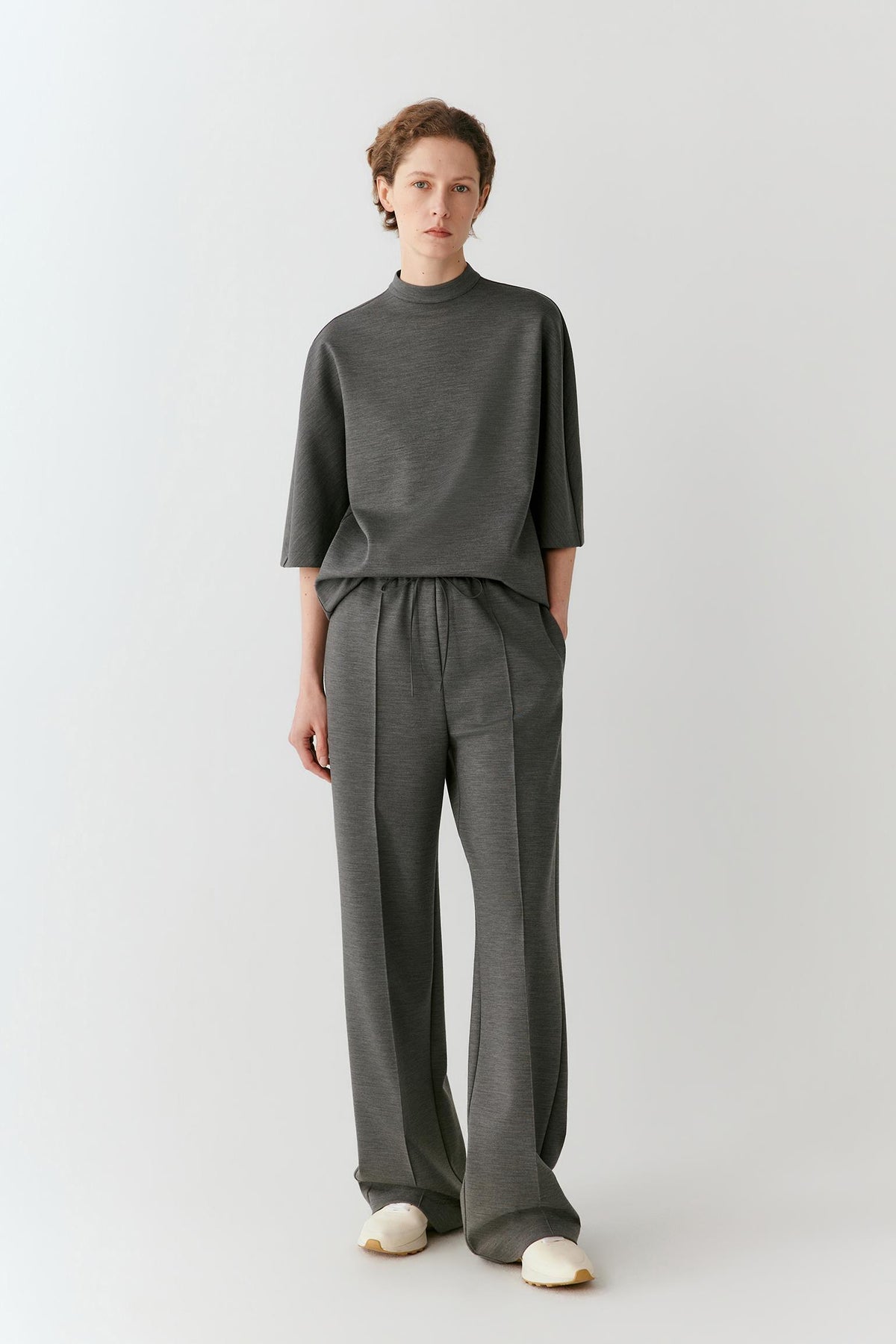 Video of a woman wearing a dark grey melange wool T-shirt, showing the elongated relaxed silhouette and movement of the Ponte di Roma jersey as she moves.