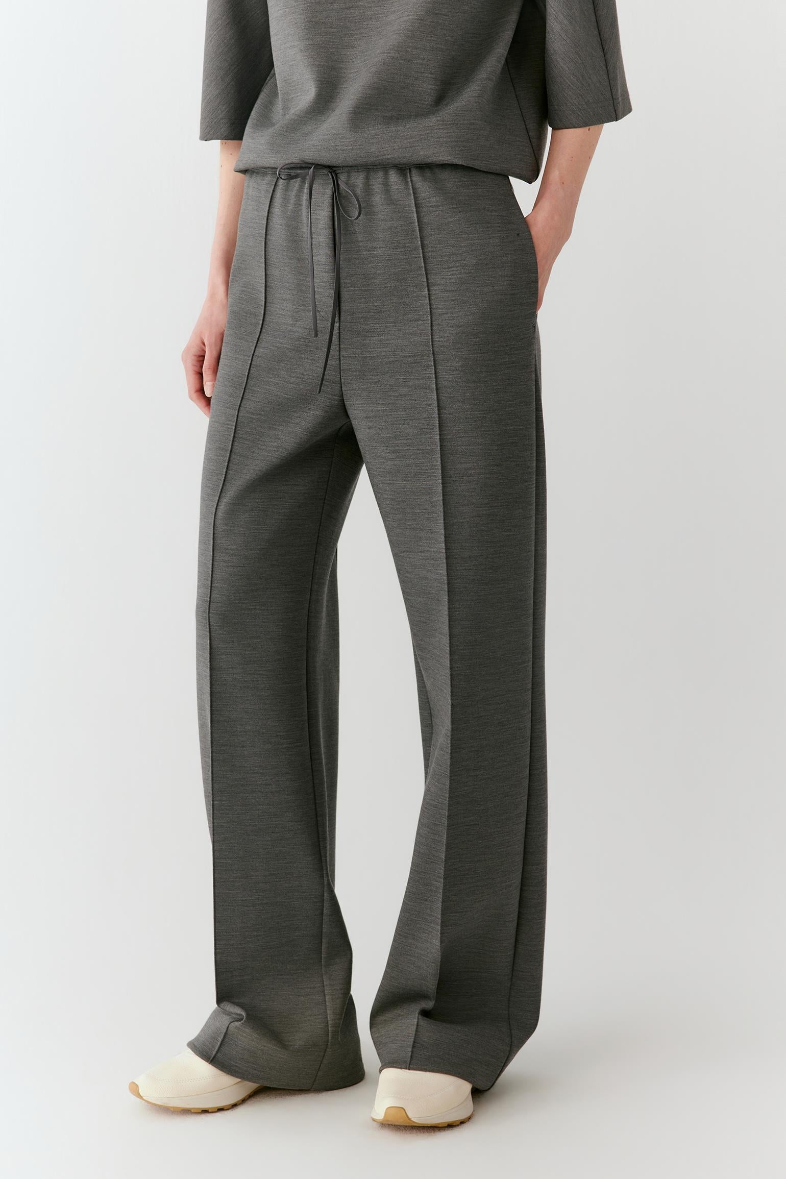Video of a woman wearing dark grey melange Ponte wool trousers, showing the straight-leg silhouette and movement of the fabric as she moves.