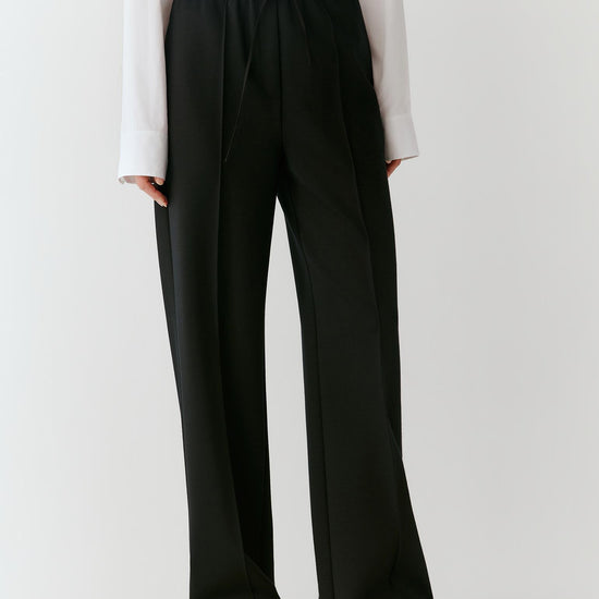 Video of a woman wearing black Ponte wool trousers, showing the straight-leg silhouette and movement of the fabric as she moves.