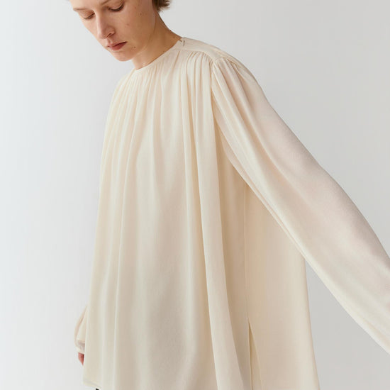 Video of a woman wearing an ivory ghost silk blouse, showing the fluid movement of the voluminous sleeves and softly gathered silhouette as she moves.