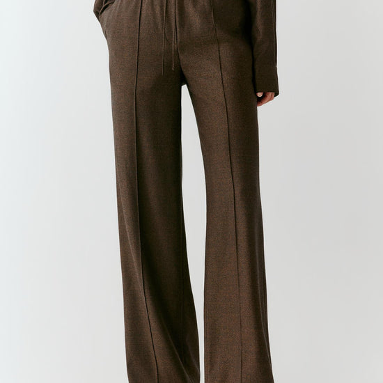Video of a woman wearing brown melange wool flannel trousers, showing the straight-leg silhouette and movement of the fabric as she moves.