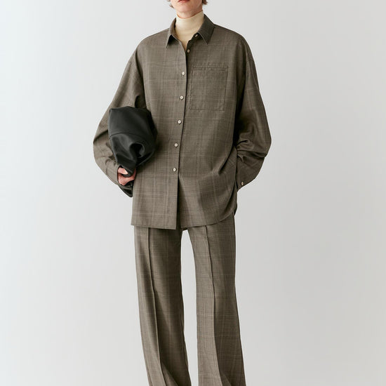 Video of a woman wearing a grey checked Glen plaid wool shirt, showing the relaxed silhouette and movement of the fabric as she moves.