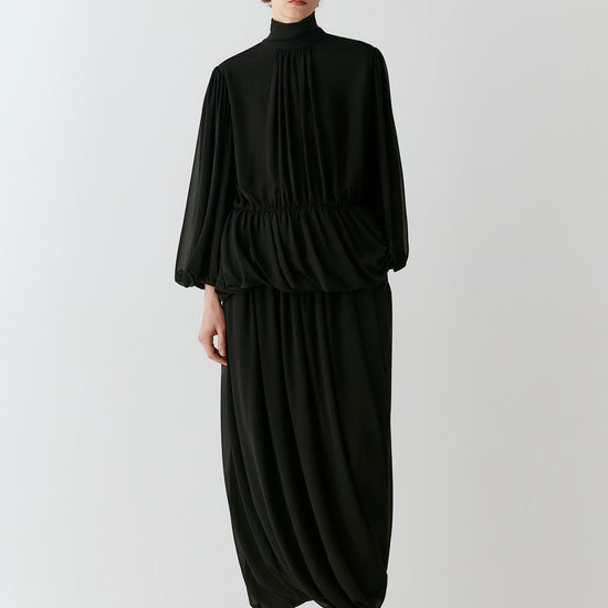 Video of a woman wearing a deep black silk georgette blouse, showing the fluid movement of the voluminous sleeves and softly gathered silhouette as she moves.