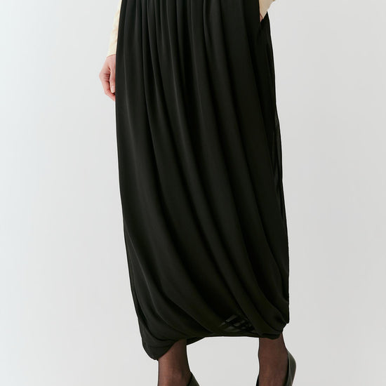 Video of a woman wearing a deep black silk georgette long skirt, showing the fluid movement and gathered volume as she moves.