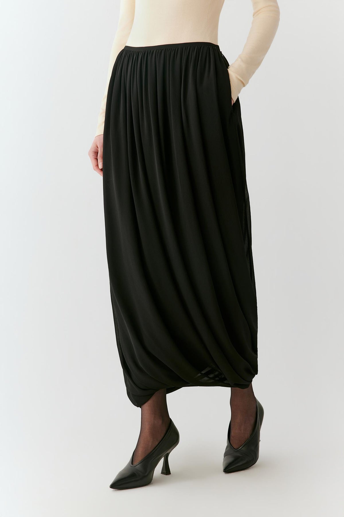 Video of a woman wearing a deep black silk georgette long skirt, showing the fluid movement and gathered volume as she moves.