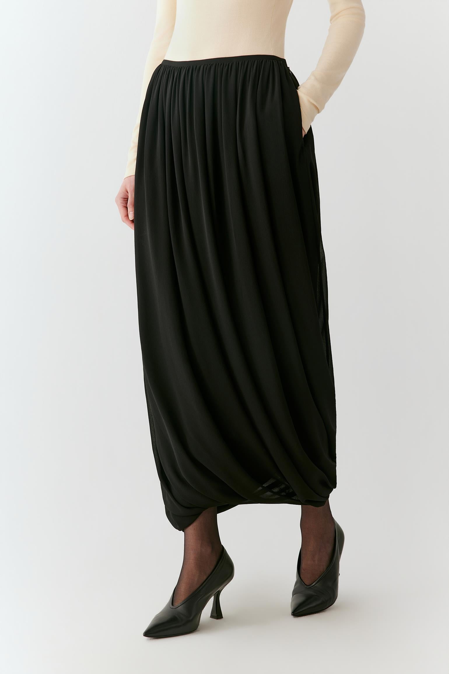Video of a woman wearing a deep black silk georgette long skirt, showing the fluid movement and gathered volume as she moves.