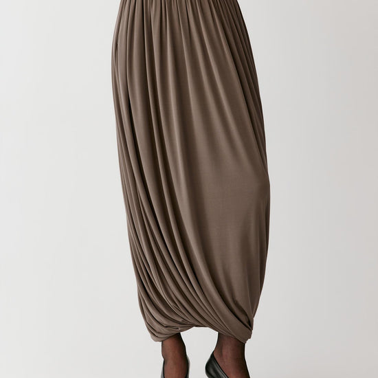 Video of a woman wearing a taupe silk long skirt, showing the fluid movement and gathered volume of the cocoon silhouette as she walks.