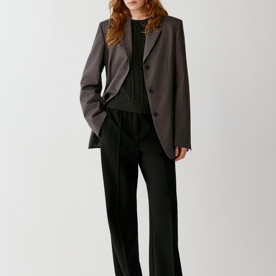 Video of a woman wearing a grey melange wool blazer, showing the movement of the straight silhouette and fluid drape as she moves.