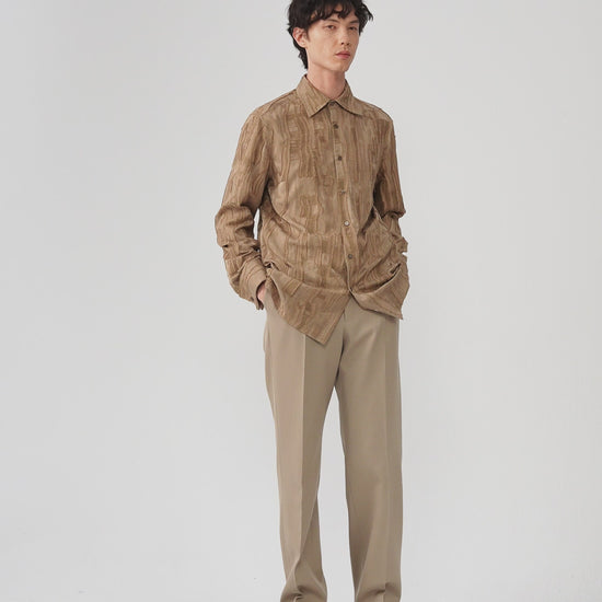 Video of a man wearing a camel jacquard shirt, showing the relaxed silhouette and movement of the textured fabric as he moves.