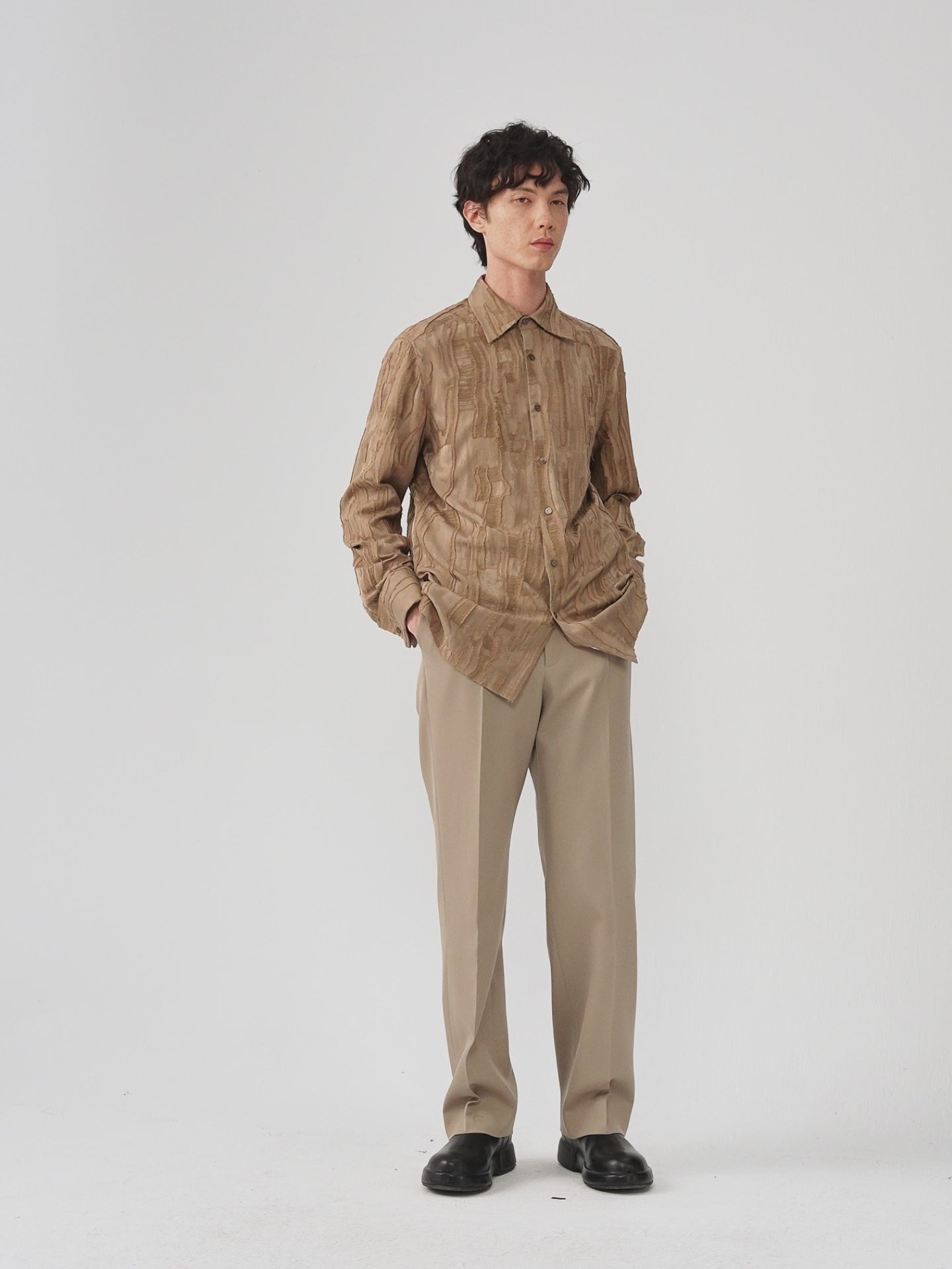 Video of a man wearing a camel jacquard shirt, showing the relaxed silhouette and movement of the textured fabric as he moves.